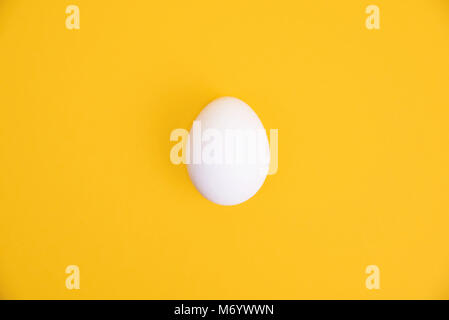 L'un des oeufs blancs sur fond jaune. Banque D'Images