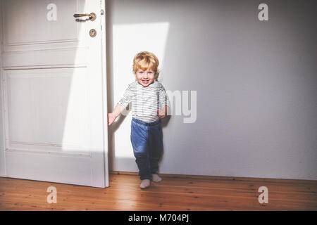 Mignon bébé garçon debout dans une chambre. Banque D'Images