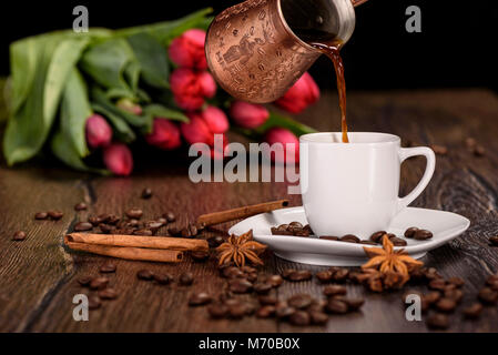 Verser le café dans une tasse blanche sur fond de tulipes close up Banque D'Images