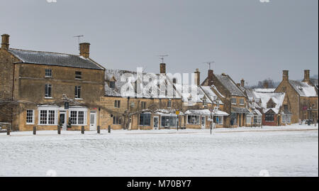 Boutiques de High Street à Broadway dans la neige d'hiver. Broadway, Cotswolds, Worcestershire, Angleterre. Panoramique Banque D'Images