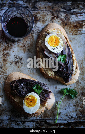 La chicorée rouge braisé crostini avec hoummos, oeuf mollet et épices Banque D'Images