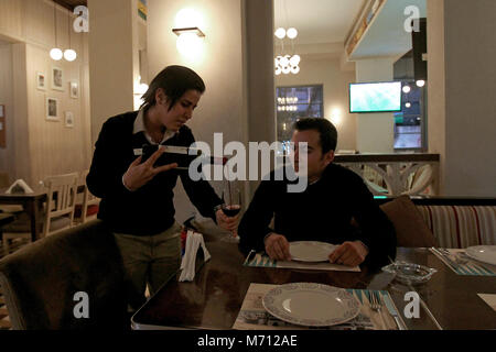 Beyrouth, Liban. 08Th Mar, 2018. Une photo disponible le 07 mars 2018 tête montre serveuse Cathy (L), 26, verse du vin à un client à Leila's Cafe à Beyrouth, Liban, 06 mars 2018. Cathy, diplômé en gestion d'entreprise, le preferrs à travailler dans l'industrie de l'accueil. Le monde célèbre la Journée internationale de la femme 2018 le 08 mars. Credit : Marwan Naamani/afp/Alamy Live News Banque D'Images