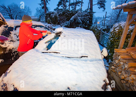 Flintshire, Pays de Galles, Royaume-Uni Météo. Après une semaine de fortes chutes de neige et des températures de gel plus de neige a diminué dans certaines régions du Royaume-Uni, y compris avec un Flintshire, Met Office d'avertissement jaune en place pour la neige avec de fortes chutes de neige dans la région. Une personne hors de la neige un pare-brise de voiture avant de travailler pendant les fortes chutes de neige dans le village d'Lixwm, Flintshire Banque D'Images