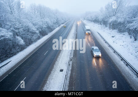 Les véhicules circulant le long d'un chemin couvert de neige A55 lorsqu'il passe dans Flintshire dans le Nord du Pays de Galles tôt le matin avec des chutes de neige et des températures de gel, ce qui rend difficile et dangereux l'hiver, Flintshire, Galles, Royaume-Uni Banque D'Images