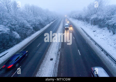 Les véhicules circulant le long d'un chemin couvert de neige A55 lorsqu'il passe dans Flintshire dans le Nord du Pays de Galles tôt le matin avec des chutes de neige et des températures de gel, ce qui rend difficile et dangereux l'hiver, Flintshire, Galles, Royaume-Uni Banque D'Images
