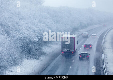 Les véhicules circulant le long d'un chemin couvert de neige A55 lorsqu'il passe dans Flintshire dans le Nord du Pays de Galles tôt le matin avec des chutes de neige et des températures de gel, ce qui rend difficile et dangereux l'hiver, Flintshire, Galles, Royaume-Uni Banque D'Images