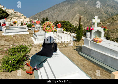 OLYMPOS, l'île de Karpathos, procession du mardi de Pâques une femme reignites la flamme d'une lampe à huile dans le cimetière Banque D'Images