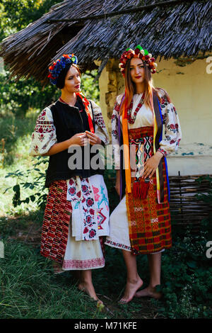 Deux belle jeune fille ukrainienne blonde and brunette dans les vêtements brodés sur fond d'une cabane en bois en été Banque D'Images