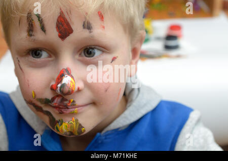 Le visage de l'enfant, de traces de peinture, de rires drôle et joyeusement Banque D'Images