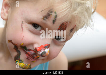 Le visage de l'enfant, de traces de peinture, de rires drôle et joyeusement Banque D'Images