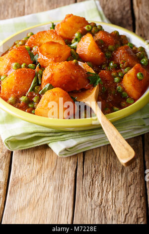 Aloo Matar indiennes épicées pommes de terre et les pois verts gros plan sur une plaque verticale sur la table. Banque D'Images