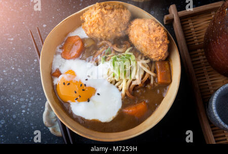 Curry japonais avec des nouilles Udon et croustillant côtelette croquettes et oeuf dur topping sur bol tasse style. Banque D'Images