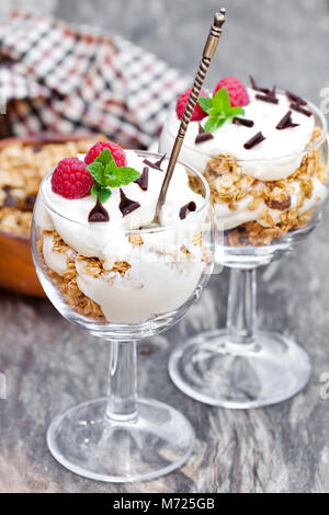 Avec Granola et crème de framboises fraîches dans un verre Banque D'Images