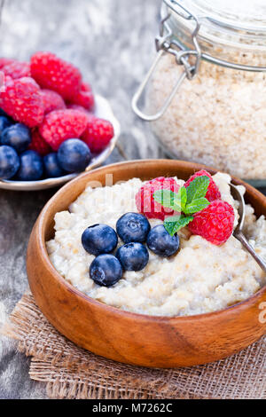 Porridge dans un bol en bois avec des baies Banque D'Images