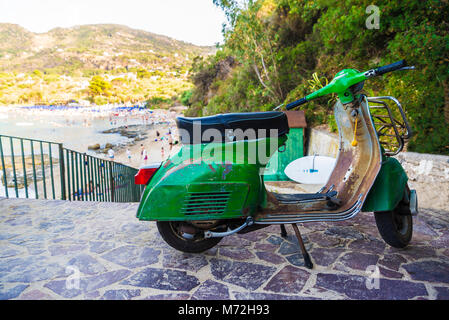 Vieille moto Vespa verte garée à côté d'une plage de Cefalù en Sicile, Italie Banque D'Images