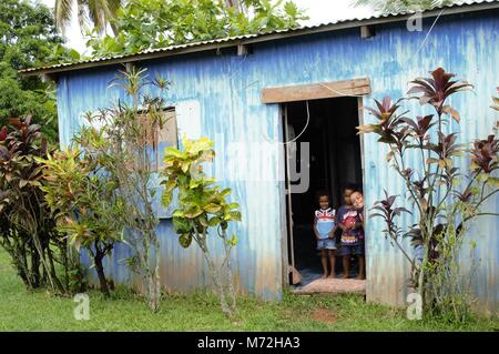 Enfants posent dans l'embrasure de la simplicité de leur accueil construit de tôle ondulée dans un village en dehors de Nadi. Banque D'Images