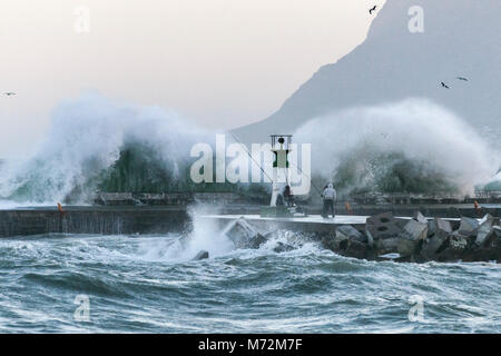 Les pêcheurs bravant les vagues énormes qui sont vus ici s'écraser contre la digue du port de Kalk Bay à Cape Town, Afrique du Sud. Banque D'Images