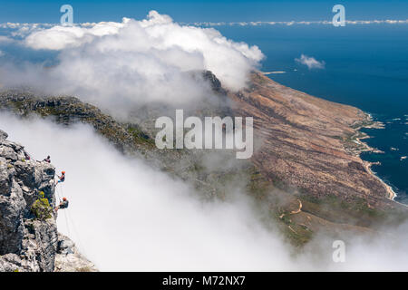 Abseilers la descente en rappel sur le sommet de la Montagne de la table avec Cap littoral atlantique en arrière-plan. Banque D'Images