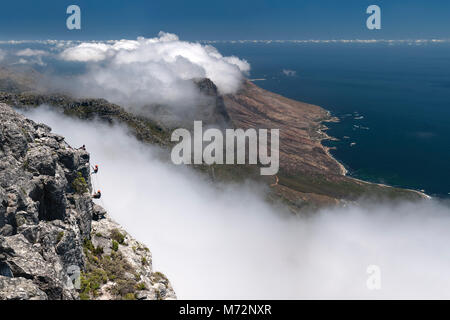 Abseilers la descente en rappel sur le sommet de la Montagne de la table avec Cap littoral atlantique en arrière-plan. Banque D'Images