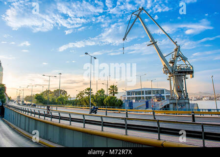 La partie vue sur le port du Pirée avec une vieille Grue et la route périphérique sous un ciel bleu au coucher du soleil Banque D'Images