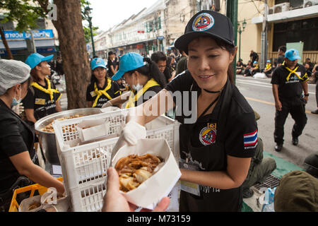 Une jeune fille bénévole offrant gratuitement de la nourriture à un participant à la crémation royale du roi thaïlandais à Bangkok Banque D'Images