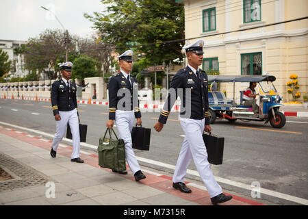 Trois jeunes officiers de l'armée thaïlandaise à pied en une seule ligne sur une rue, avec un tuk tuk passant par en arrière-plan, le jour après la crémation royale Banque D'Images