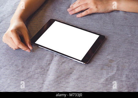 Immersive image d'une personne à l'aide du noir tablet pc avec écran de bureau blanc vierge sur la table Banque D'Images