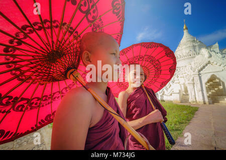 MANDALAY, MYANMAR, -11 décembre 2017 : Deux jeunes Asiatiques non identifiés monk holding parapluies rouges sur la Mya Thein Tan Mingun pagode à Mandalay, Myanmar Banque D'Images