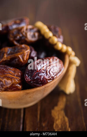 Dates fraîches Fruits au bol en bois sur fond de bois Banque D'Images