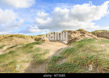 Vallées des dunes avec des trous de vent profond creusé par forte tempête de sable avec des herbes, l'ammophile nuages épars contre le ciel bleu Banque D'Images