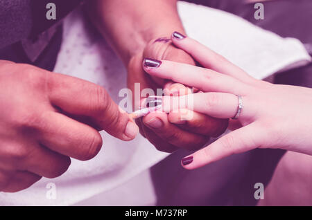 Manucure enlever le surplus d'encre à partir de la Polish ongles après peinture à l'aide d'un bâton en bois avec du coton sur la pointe. Peinture vernis à ongles violet proced Banque D'Images