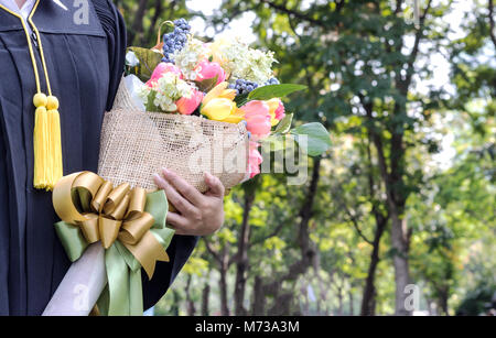 Student graduate holding Flower bouquet dans la main Banque D'Images