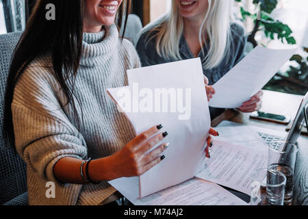 Businesswoman signe un contrat dans un café à une table en bois Banque D'Images