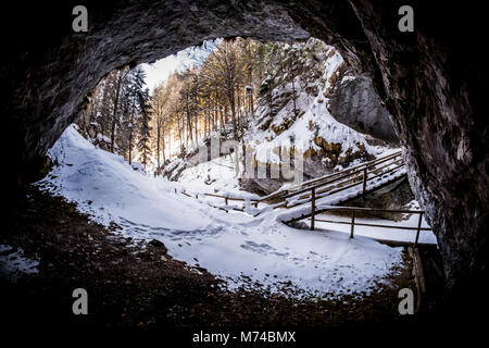 Voir à partir de la grotte sombre à Baerenschuetzklamm gorge couverte de neige avec la forêt et pont de bois en hiver Banque D'Images