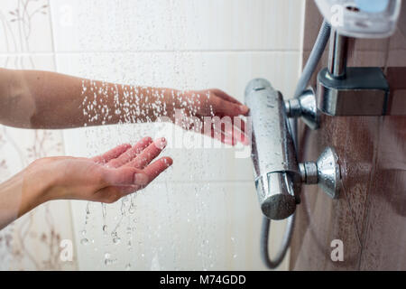 Mains d'une jeune femme prenant une douche chaude à la maison Banque D'Images