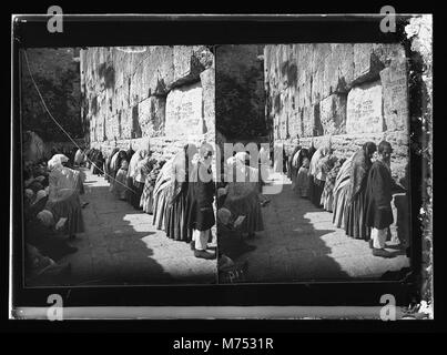 Photographie d'individus juifs priant au mur occidental, également connu sous le nom de mur des lamentations, à Jérusalem. Le site est un point de repère religieux important pour le judaïsme, où les fidèles se rassemblent pour prier et déposer des notes dans les crevasses du mur dans le cadre de leur pratique spirituelle. Banque D'Images