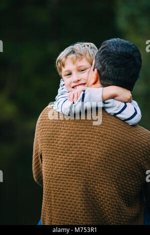 Petit garçon est être caressé par son père tandis que l'extérieur. Banque D'Images