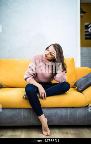 Photo d'un débraillé fatigué femme assise sur la table il à la maison. Girl regarder TV nouvelle série. Canapé relax concept après une dure journée de travail. Femme assise attentive sur canapé à la maison s'ennuie Banque D'Images