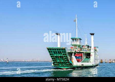 Vue de la lumière du jour chargé vert croisière ferry sur l'eau avec des traces près de port. Les bâtiments et autres bateaux sur l'arrière-plan. Ciel clair bleu vif. Effets négatifs Banque D'Images