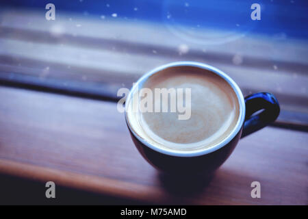 Americano café sur un côté de la fenêtre et la neige qui tombe en hiver. selective focus, vintage style photographique et cinématographique. Banque D'Images