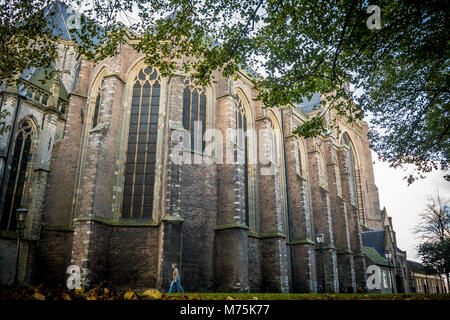 Dordrecht, Pays-Bas - le 27 octobre 2018 : une femme marche par le vieux quartier gothique Grote Kerk une journée d'automne. Banque D'Images