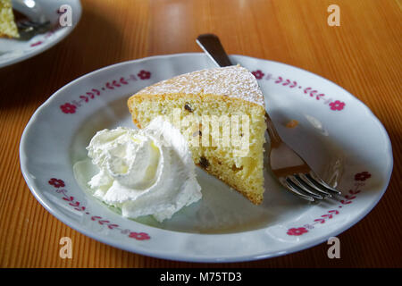Gâteau éponge avec de la crème sure et la fourchette sur l'assiette blanche sur une table en bois, de l'alimentation arrière-plan. Banque D'Images
