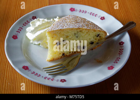 Gâteau éponge avec de la crème sure et la fourchette sur l'assiette blanche sur une table en bois, de l'alimentation arrière-plan. Banque D'Images