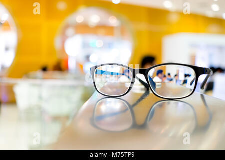 Les lunettes sur la table dans une bibliothèque, peuvent voir des gens lire des livres à travers l'objectif Banque D'Images