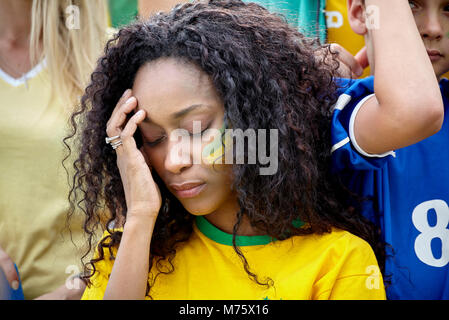 Femme tenant tête en déception à match de football brésilien Banque D'Images