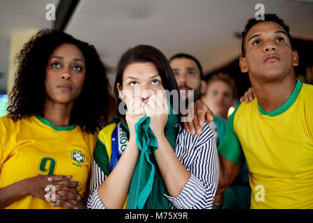 Les supporters de football brésilien regardant anxieusement match à bar Banque D'Images