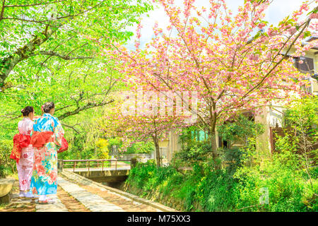 Deux femmes asiatiques en kimono prendre photo de cerisiers le long de promenade du Philosophe au cours de Sakura, spécial printemps saison. Le chemin est un célèbre sentier piétonnier dans le quartier Higashiyama, Kyoto, Japon. Banque D'Images