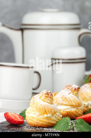 Profiteroles à la crème, des fraises et du sucre en poudre. De délicieux gâteaux faits de pâte à choux. Selective focus Banque D'Images
