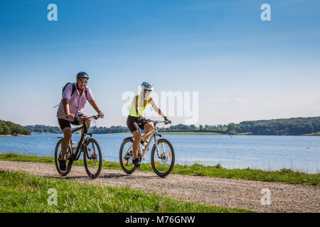 Man and Woman riding leurs VTT le long d'un chemin au bord du lac par temps ensoleillé Banque D'Images