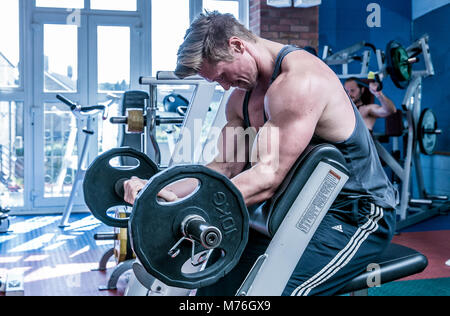 Homme travaillant sur musculaire avec des poids dans la salle de sport Banque D'Images